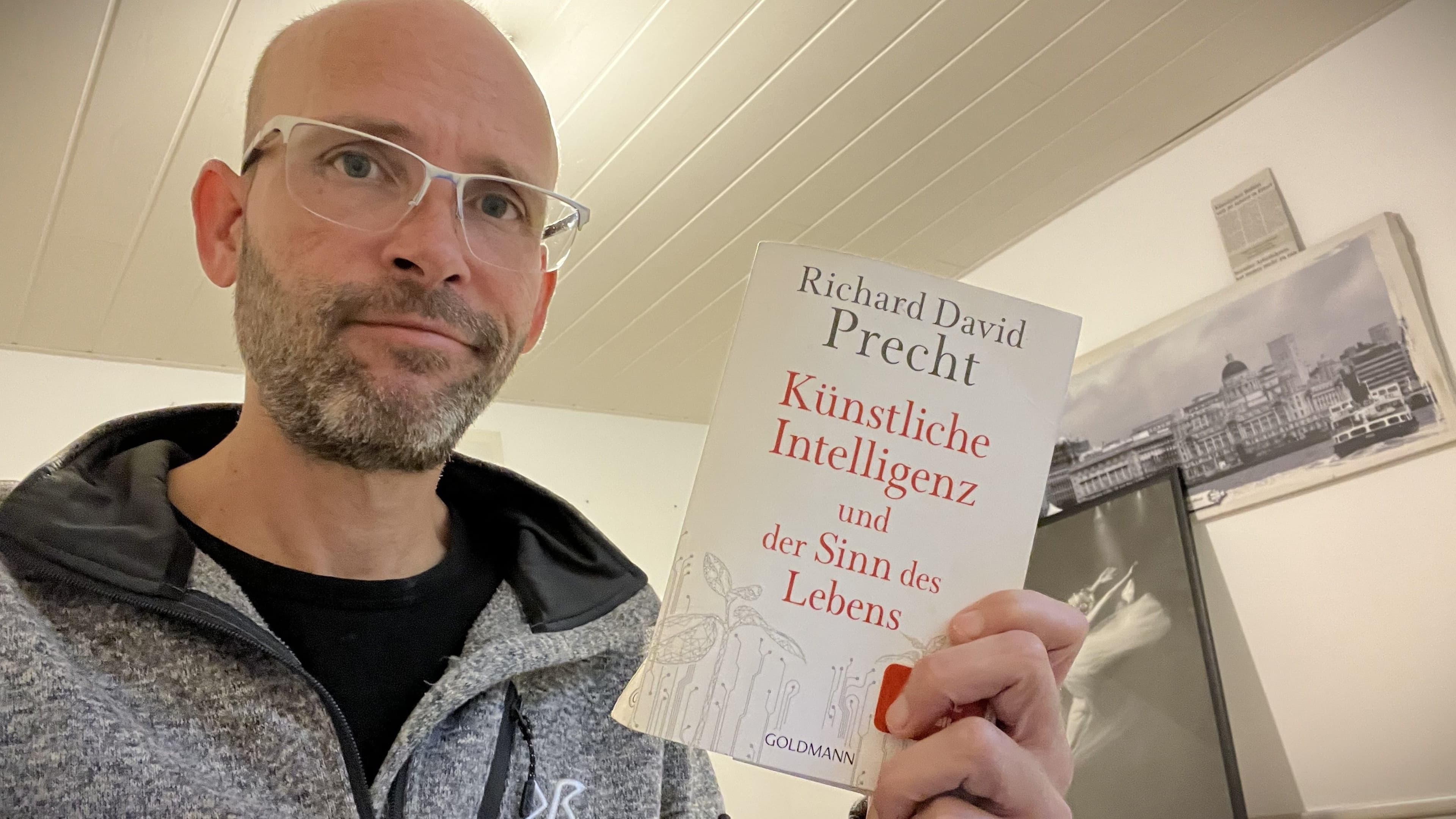 Sean Kollak hält Richard David Prechts Buch Künstliche Intelligenz und der Sinn des Lebens in die Kamera – Ausgangspunkt eines Essays über Reibung, Widerstand und die Anstrengung, durch die ein Selbst erst entsteht.